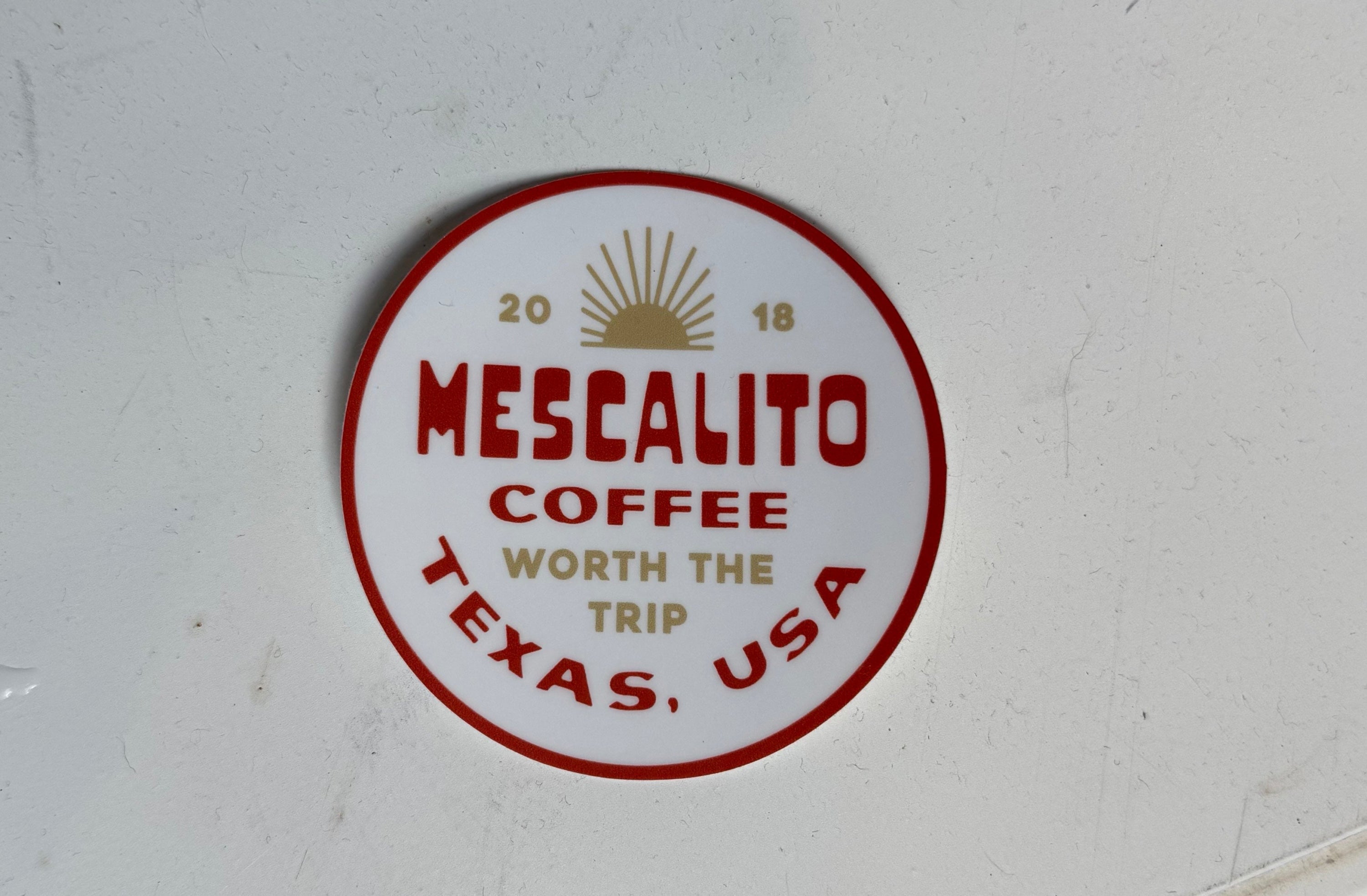 The Shop Stickers | Mescalito Coffee by Mescalito Coffee feature a round design with "Mescalito Coffee Worth the Trip, Texas, USA, 2018" and a sun graphic on white—ideal for capturing coffee shop charm and small-town vibes.